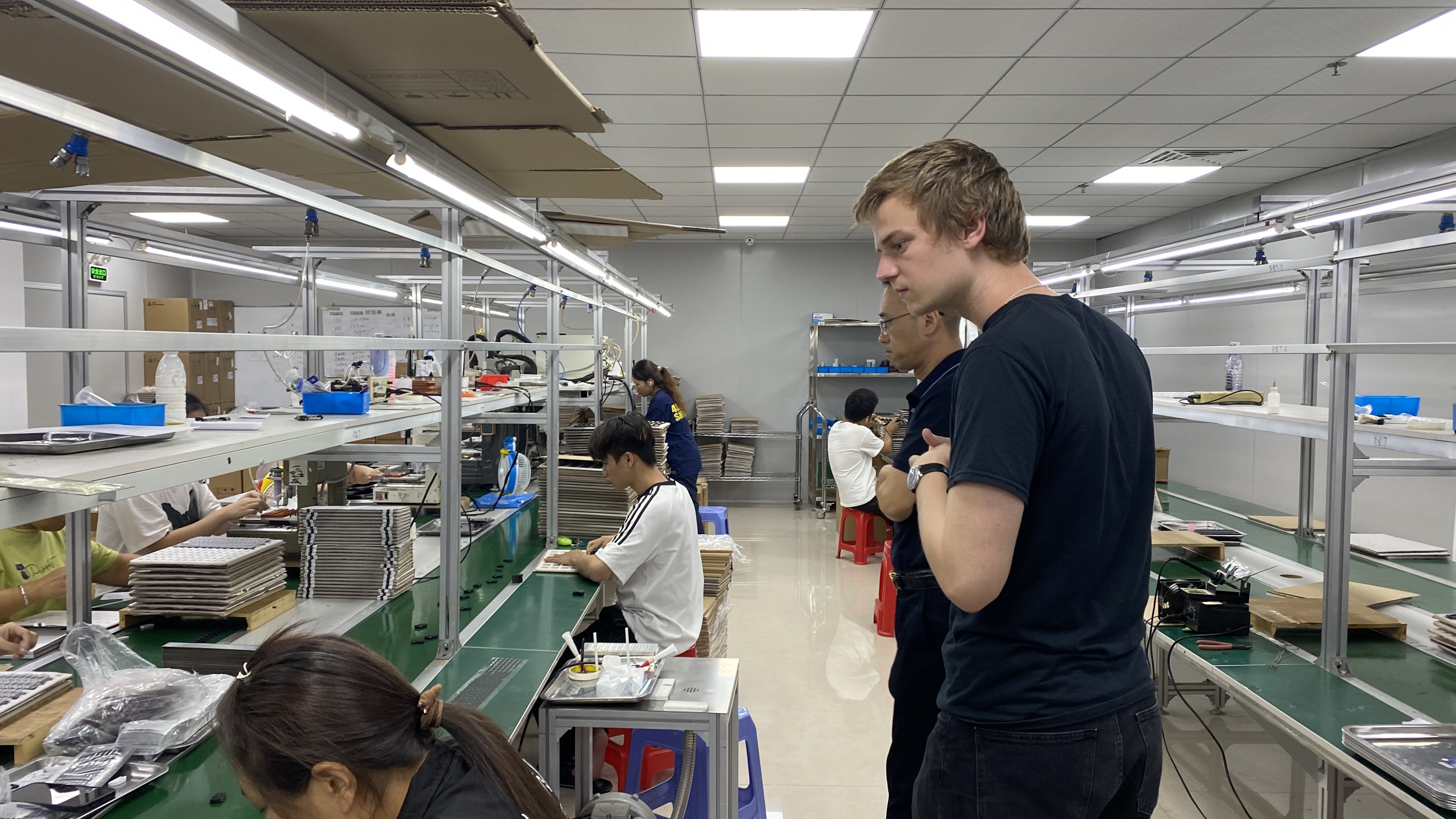 A visitor observing work on a Shenzhen factory floor