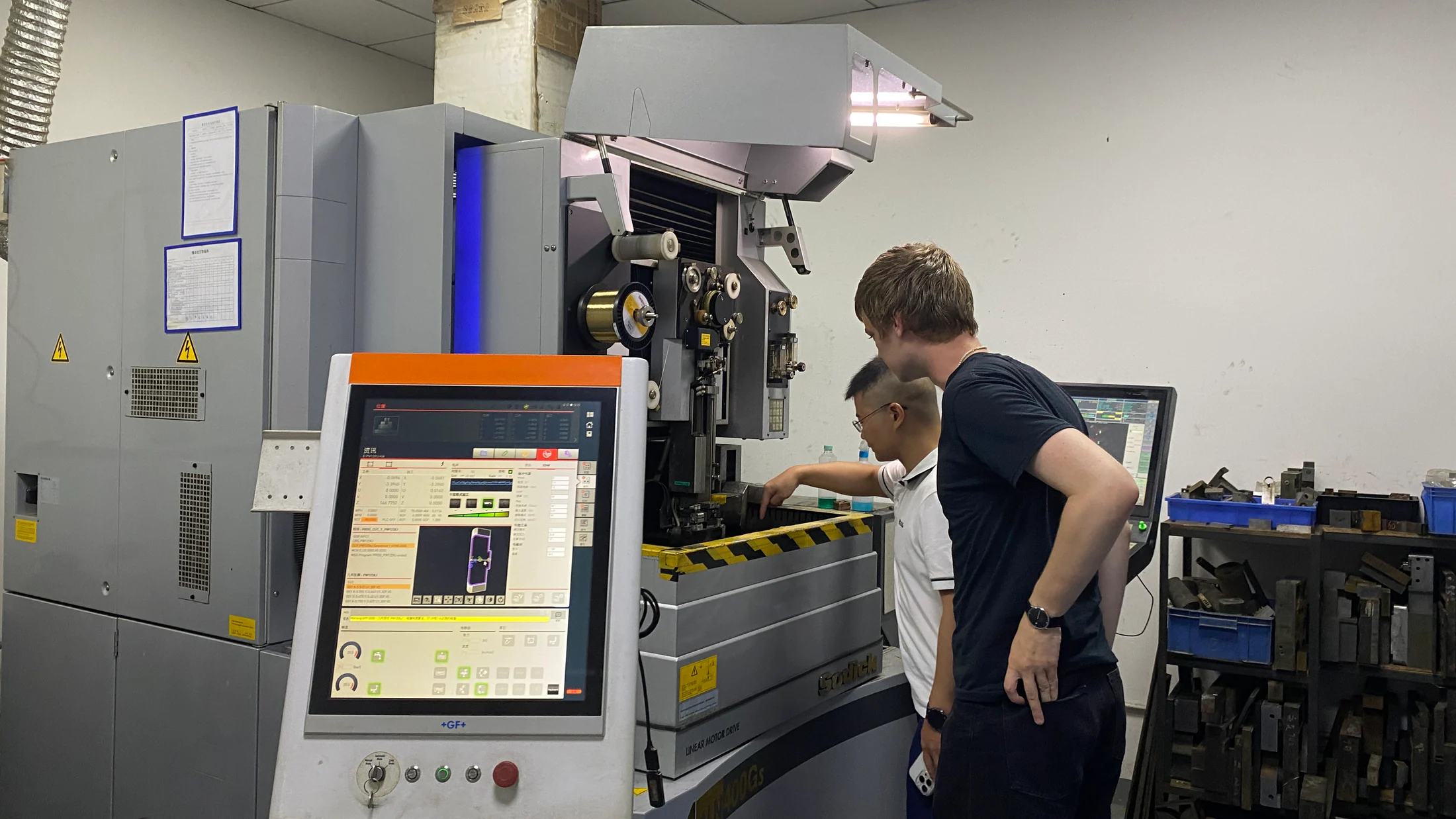 A hardware founder reviewing precision manufacturing equipment in a Shenzhen factory